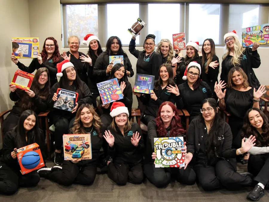 The Sala team holding donated toys for their holiday toy drive.